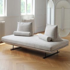 a white couch sitting on top of a hard wood floor next to a wall mounted mirror