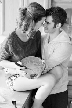 black and white photograph of a couple kissing in the kitchen