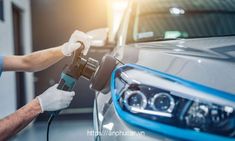 a man in blue shirt and white gloves waxing a car's headlight