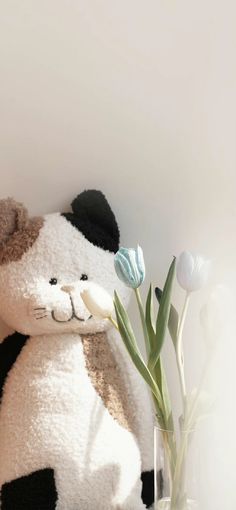 there is a stuffed teddy bear next to a vase with tulips