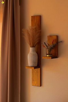 two wooden shelves with vases and plants on them in front of a beige wall