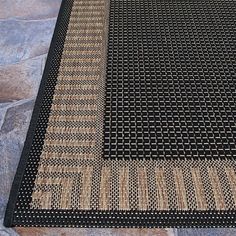 a black and tan area rug sitting on top of a stone floor