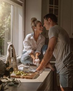 a man and woman standing in front of a kitchen counter with food on the counter