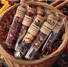 four bottles filled with different types of spices in a wicker basket next to cinnamon sticks