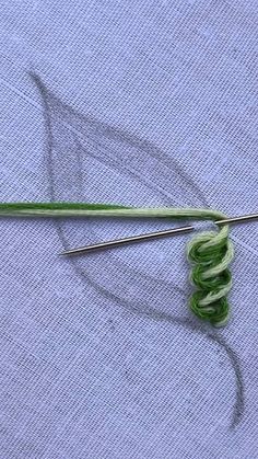 a pair of knitting needles sitting on top of a piece of cloth