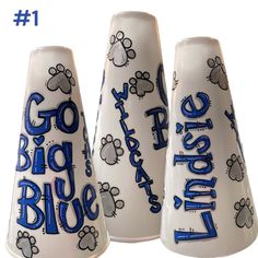 three white vases with blue writing and paw prints on them, one is for the dog