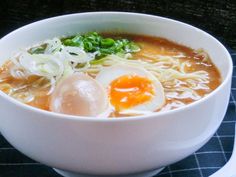 a bowl of ramen with an egg on top and noodles in the middle, next to a spoon