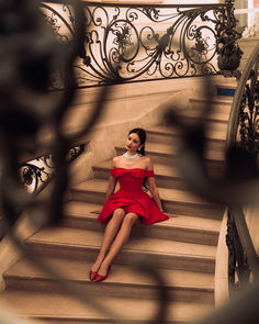 a woman in a red dress sitting on some stairs