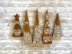 three wooden christmas trees with white designs on them