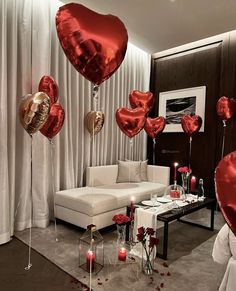 red and gold heart balloons floating in the air over a living room with white couches