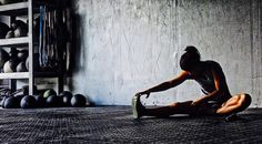 a woman kneeling on the floor in front of a rack of kettles and exercise equipment