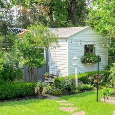 a small white house surrounded by trees and flowers