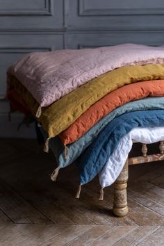 a stack of blankets sitting on top of a wooden bench