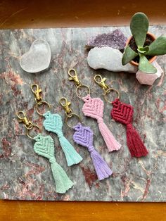 four tasseled key chains on a marble slab next to a potted plant