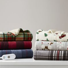 several folded blankets are sitting on a shelf next to an electric thermostaer