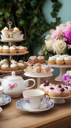 a table topped with cupcakes and cakes next to a vase filled with flowers