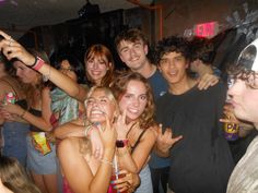 a group of young people standing next to each other in front of a crowd at a party