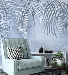 a blue chair sitting in front of a wall with palm leaves on it