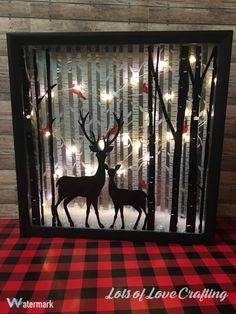 the silhouettes of two deer are on display in a shadow box with christmas lights behind them