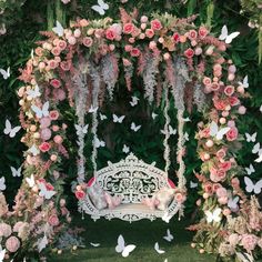 a white bench surrounded by pink flowers and butterflies