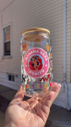 a person holding up a glass jar with an image on it