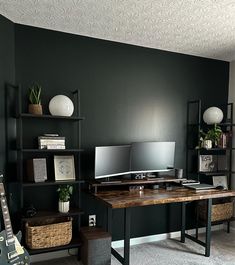 a computer desk with two monitors and a guitar