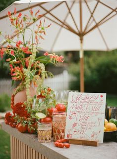 a table topped with lots of different types of fruits and vegetables next to a white umbrella