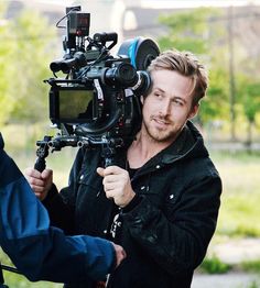 a man standing next to a camera on top of a tripod