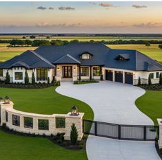 an aerial view of a large home in the middle of a grassy area with a driveway leading to it