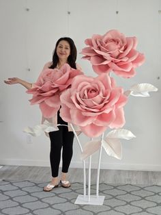 a woman standing in front of a pink flower sculpture