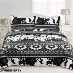 a bed with a black and white comforter on top of it next to a night stand