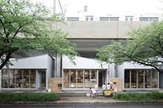 two people are walking down the sidewalk in front of a building