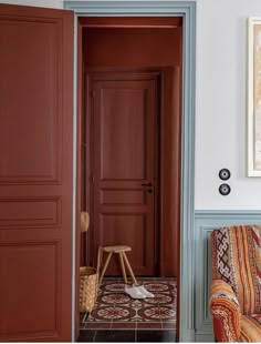 an open door leading to a living room with a patterned chair and rug on the floor