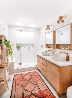 a bathroom with two sinks and a large rug on the floor in front of it