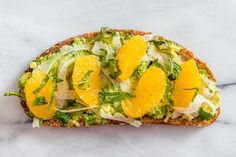 an open face sandwich with oranges, lettuce and other vegetables on it