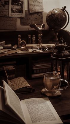 an open book sitting on top of a wooden table next to a cup of coffee