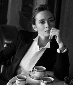 a woman sitting at a table with cups and saucers in front of her face