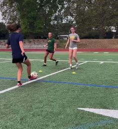 three girls are playing soccer on the field