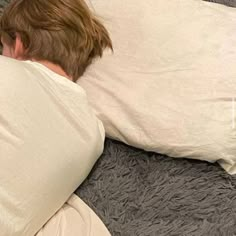 a man laying in bed with his back turned to the side, under a pillow