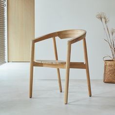 a wooden chair sitting in front of a window next to a basket with flowers on it