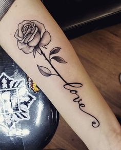 a rose with the word love tattooed on it's arm is shown in black ink