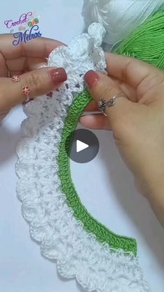 two hands crocheting a piece of white and green yarn