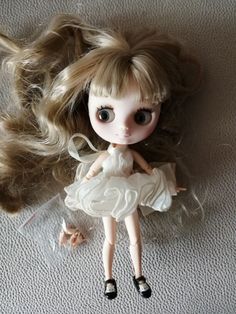 a doll is laying on the floor with her hair blowing in the wind