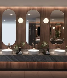 there are three sinks in the bathroom with mirrors on the wall above them and two planters