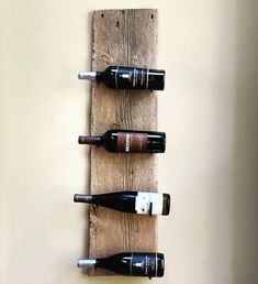 three bottles of wine are hanging on a wooden wall mounted wine rack that is made out of wood planks