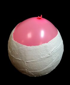 a pink and white balloon sitting on top of a black surface