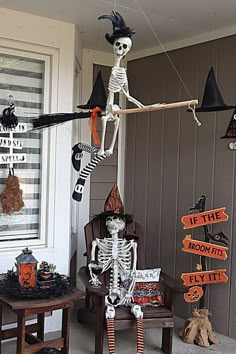 a skeleton sitting on top of a chair in front of a house decorated for halloween