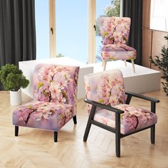 two chairs with pink flowers on them in front of a window and potted plant