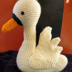 a crocheted white duck sitting on top of a black blanket