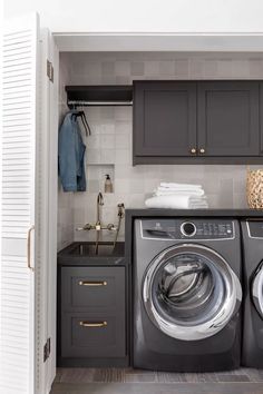 a washer and dryer in a small laundry room with dark wood cabinets on the wall